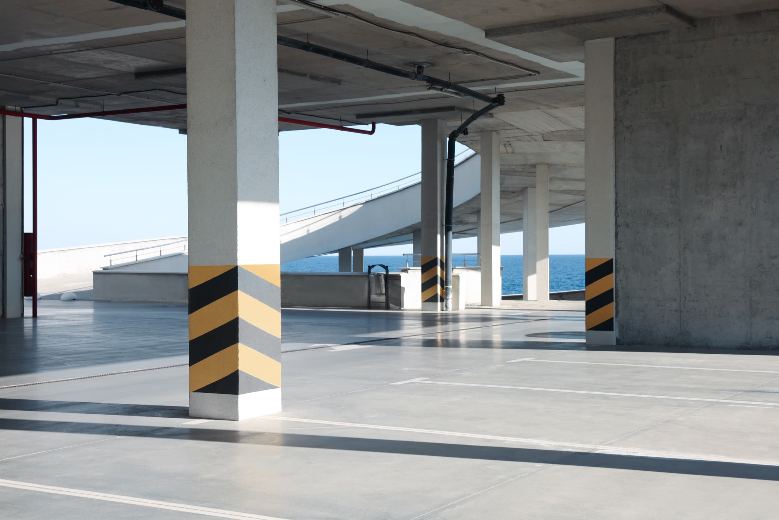 Empty open-sided parking garage deck with striped support columns and a ramp