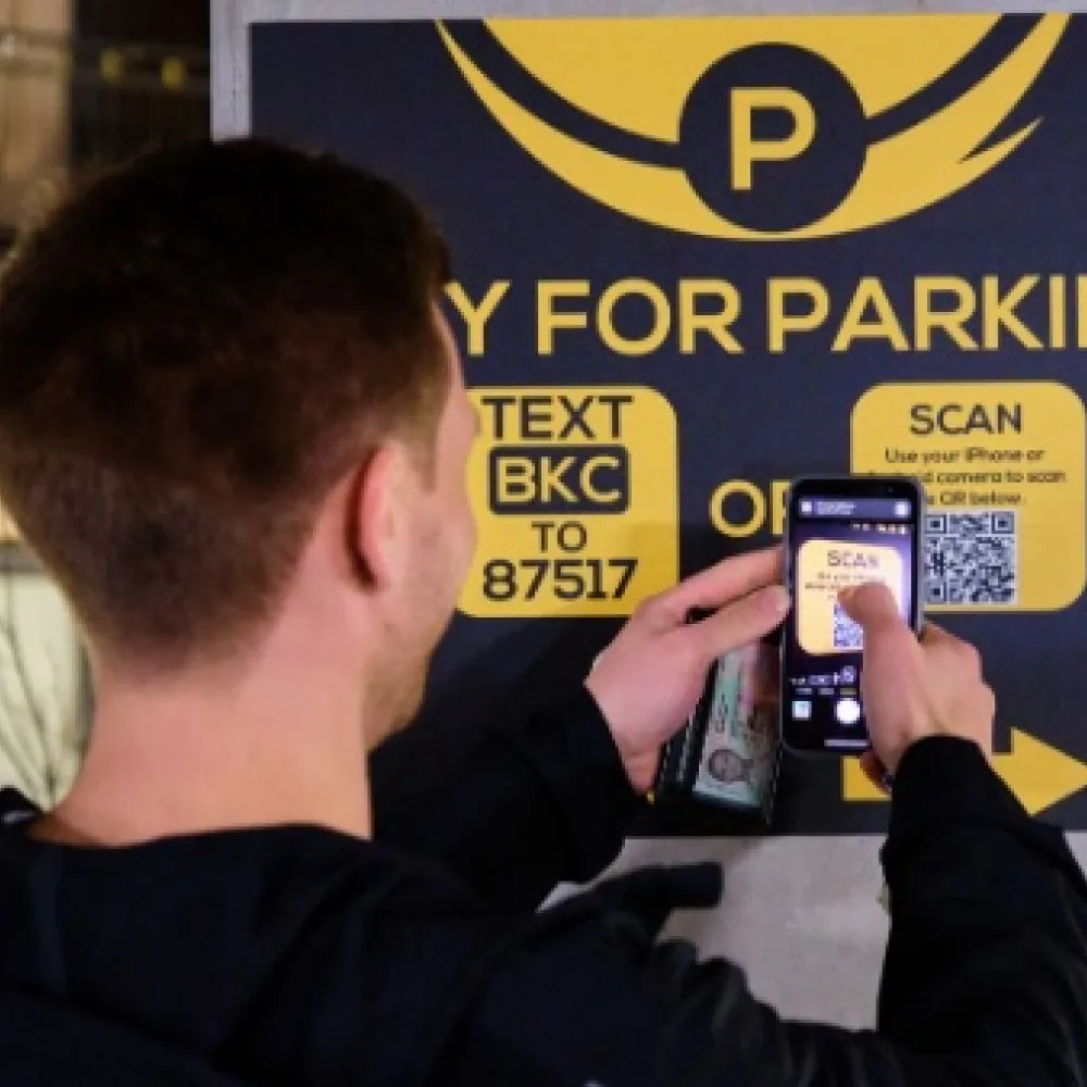 A person using their phone to scan a QR code in order to pay for parking.
